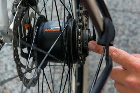 Hand stellt die Shimano Nabenschaltung ein. Ein kleiner gelber Strich ist sichtbar.