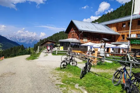 Bergpanorama in den Tuxer Alpen mit Holzhütte, Fahrrädern und E-Bike-Tankstelle.
