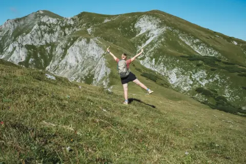 Glückliche Wanderin mit erhobenen Armen und Stöcken genießt die Aussicht auf die Berge beim Wandern in Polen.