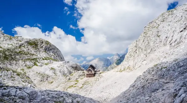Hütte in den Julischen Alpen, idealer Rastplatz für eine Triglav Wanderung. Majestätische Berglandschaft unter blauem Himmel.