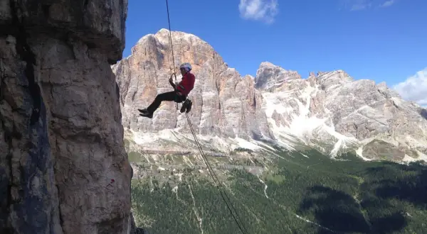 Abseilen in den Dolomiten: Ein Kletterer seilt sich vor majestätischer Bergkulisse ab.