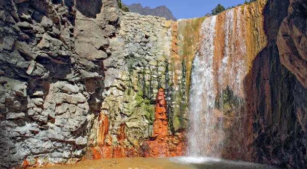 Farbenprächtiger Wasserfall mit rostfarbenen Felsen, ideal für la palma wandern. Ein Naturjuwel.