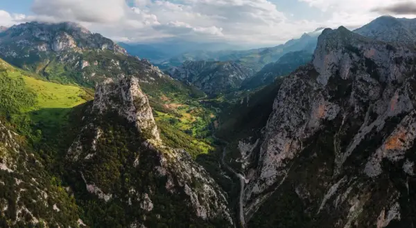 Majestätische Berge der Picos de Europa, grüne Täler und eine Straße, die sich durch die Schlucht schlängelt.