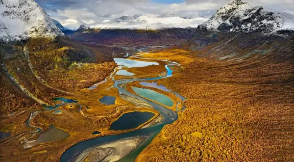 Herbstliche Landschaft mit Flüssen und Seen, ideal für fernwanderwege schweden. Schneebedeckte Berge im Hintergrund.