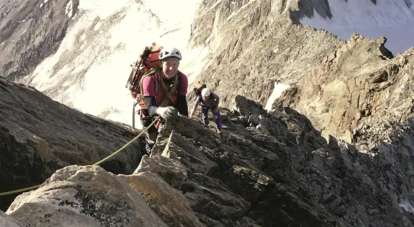 Zwei Bergsteiger klettern gesichert über den Normalweg am Lagginhorn. Die felsige Route führt durch steiles Gelände mit Schneefeldern im Hintergrund.