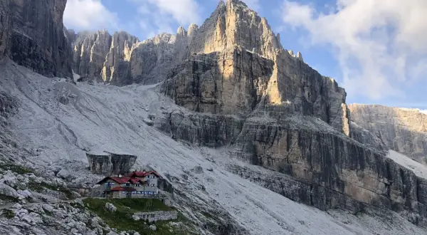 Hütte in den Brenta Dolomiten, umgeben von steilen Felswänden und Geröllfeldern. Ein majestätischer Anblick.