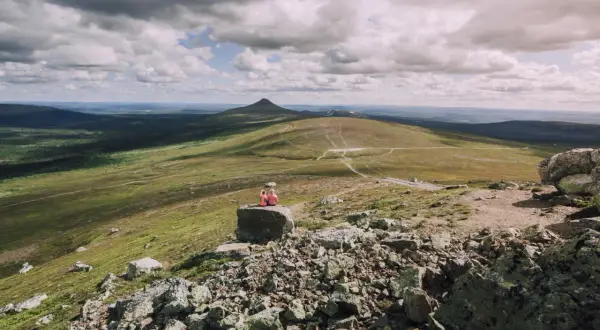 Zwei Wandererinnen genießen die weite Aussicht auf eine Berglandschaft in Schweden. Die Wolkenformationen am Himmel sind dramatisch.