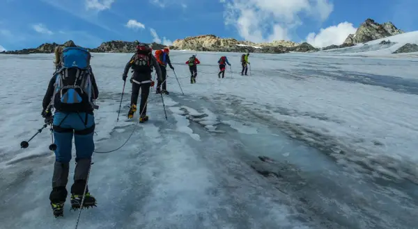 Bergsteiger seilen sich auf dem Weg zum Piz Buin über einen eisigen Gletscher ab.