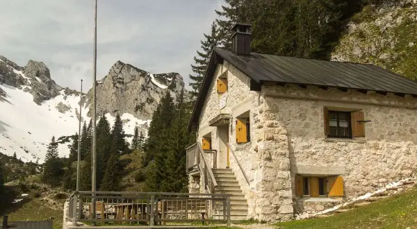 Steinernes Haus mit Holzterrasse und Bergkulisse im Tannheimer Tal. Ein Geheimtipp für Wanderer.