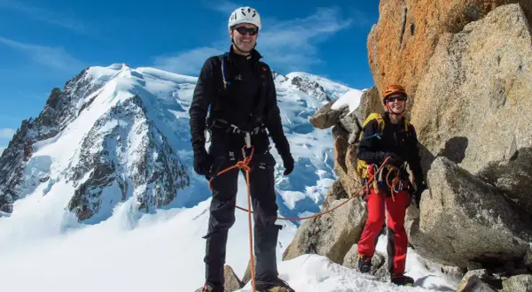 Zwei Bergsteiger auf dem Weg zur Mont Blanc Besteigung, umgeben von Schnee und Felsen.