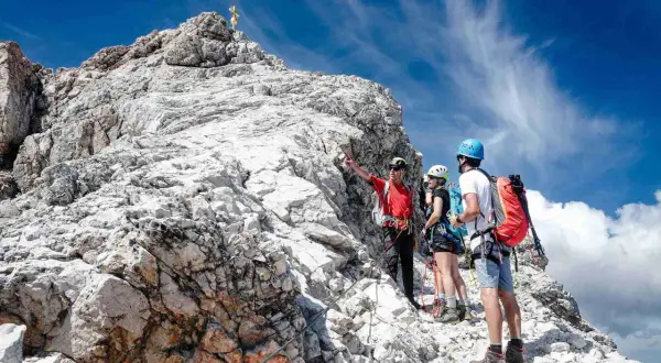 Bergsteiger erklären den Weg zur Zugspitze ohne Klettersteig. Ein Führer zeigt auf den Gipfel.
