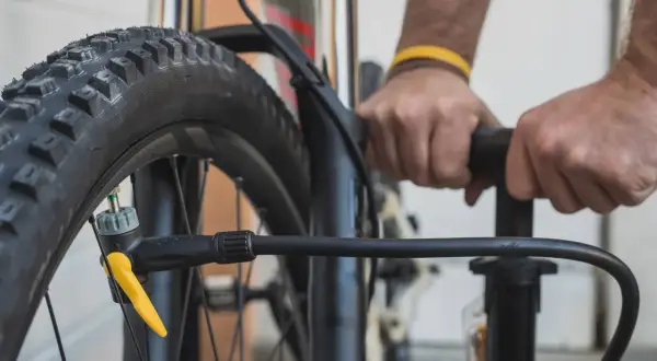 Hände pumpen einen Reifen auf. Der richtige Reifendruck für ein Fahrrad mit 20 Zoll Rädern ist wichtig für die Fahrt.