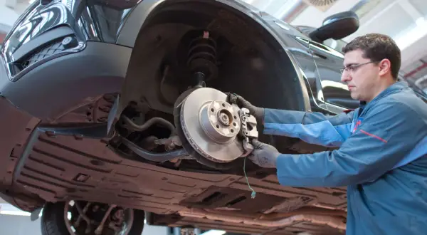 Mechaniker arbeitet am quietschenden Vorderrad eines Autos.