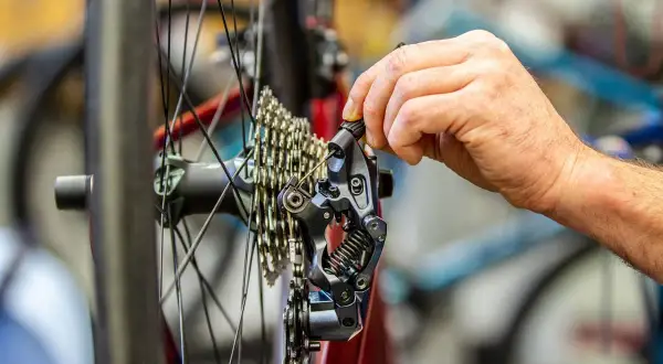 Hand stellt Shimano 105 Schaltwerk ein. Präzise Justierung für reibungsloses Schalten.