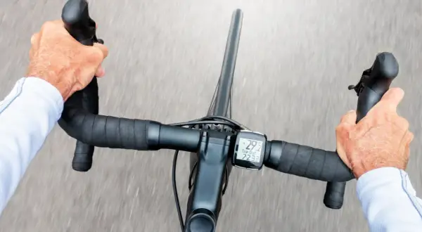 Hände greifen den Rennradlenker, während der Radcomputer 29,2 km/h anzeigt.