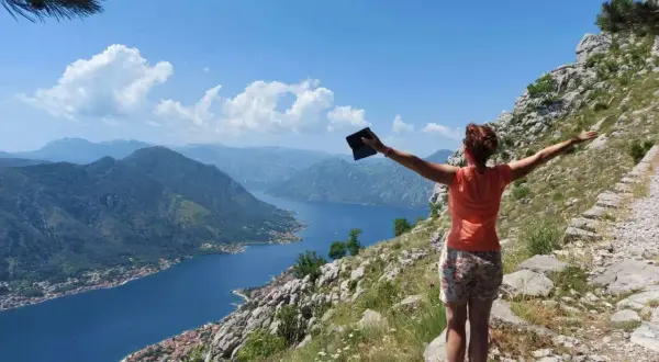 Frau genießt die Aussicht beim **Montenegro wandern**. Der Blick schweift über die Bucht von Kotor, umgeben von Bergen.