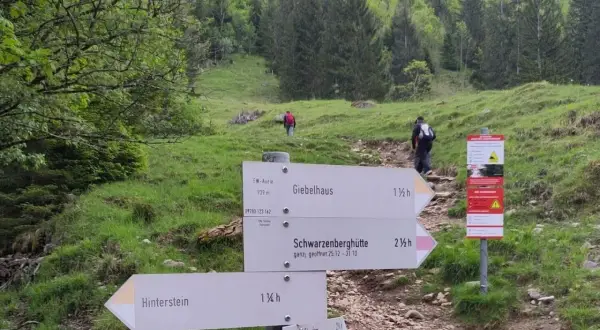 Wegweiser für eine Schrecksee Wanderung: Giebelhaus, Schwarzenberghütte und Hinterstein sind Ziele. Wanderer steigen bergauf.