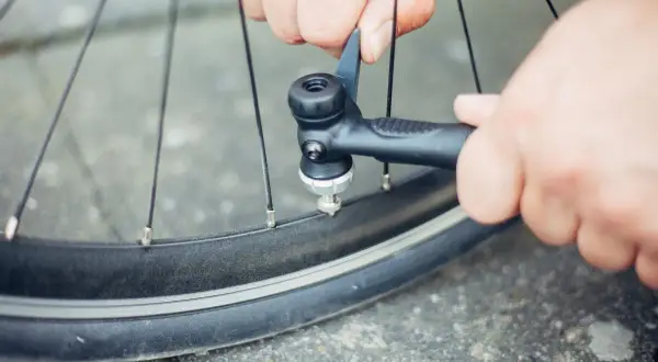 Hände versuchen, ein Fahrradventil aufzupumpen, aber es scheint, als ob das Dunlop Ventil aufpumpen geht nicht.