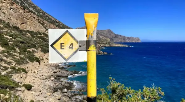 Wegweiser E4 auf Kreta, mit Blick auf das tiefblaue Meer und die felsige Küste.