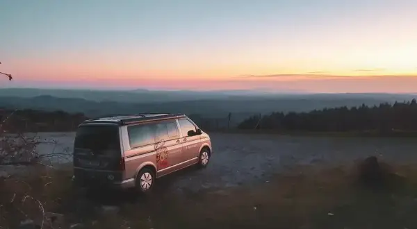 Ein Campervan steht auf einem Hügel bei Sonnenuntergang. Die Frage "was kostet wildcampen" stellt sich hier nicht, denn die Aussicht ist unbezahlbar.