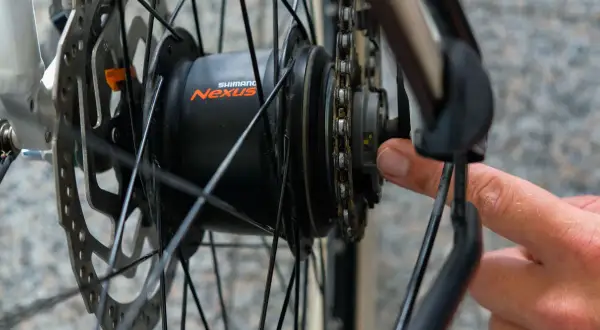 Hand stellt die Shimano Nabenschaltung ein. Ein kleiner gelber Strich ist sichtbar.
