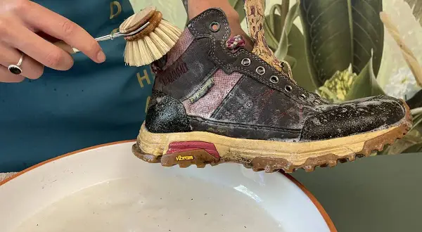 Schmutzige Wanderschuhe reinigen mit einer Bürste und Seifenwasser.