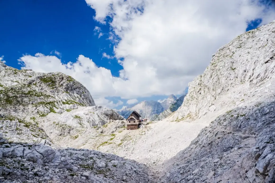 Hütte in den Julischen Alpen, idealer Rastplatz für eine Triglav Wanderung. Majestätische Berglandschaft unter blauem Himmel.