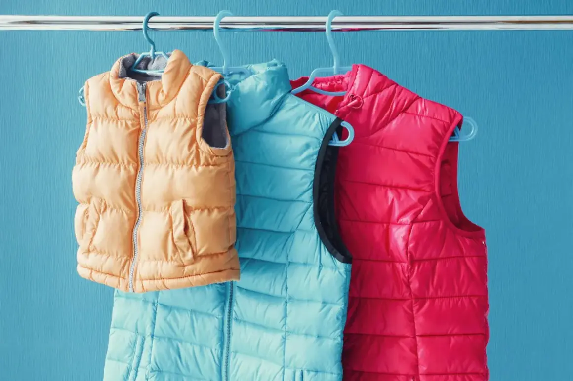 Drei Steppwesten in Orange, Türkis und Pink hängen an Kleiderbügeln. So waschen Sie Ihre daunenjacke waschen ohne trockner.