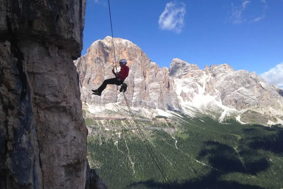 Abseilen in den Dolomiten: Ein Kletterer seilt sich vor majestätischer Bergkulisse ab.