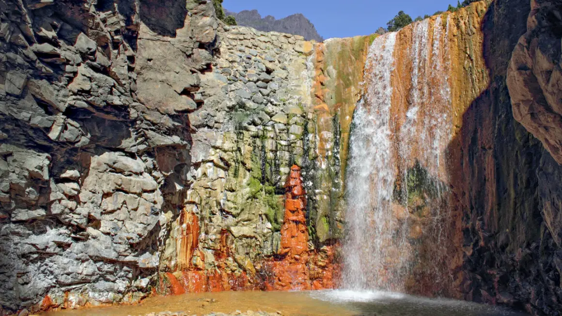Farbenprächtiger Wasserfall mit rostfarbenen Felsen, ideal für la palma wandern. Ein Naturjuwel.