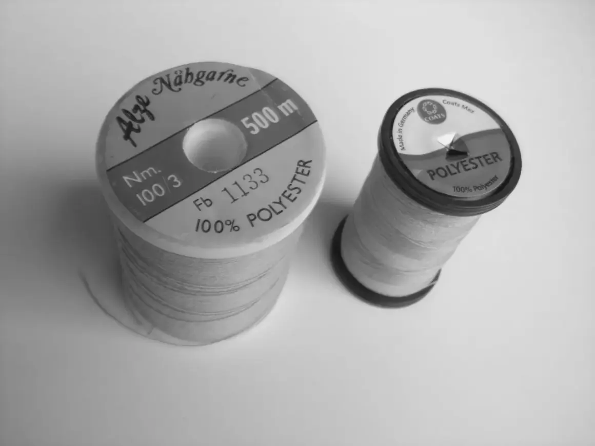 Zwei Garnrollen, eine "Alze Nähgarne" mit 500m, die andere "Coats Mez Polyester". Beide sind aus 100% Polyester, was ihre Bedeutung für Haltbarkeit und Vielseitigkeit unterstreicht.