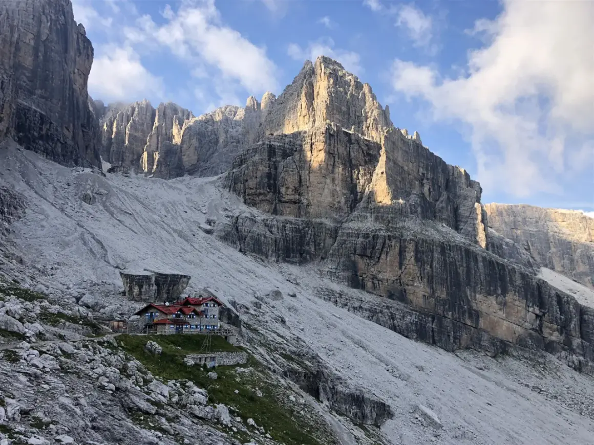 Hütte in den Brenta Dolomiten, umgeben von steilen Felswänden und Geröllfeldern. Ein majestätischer Anblick.