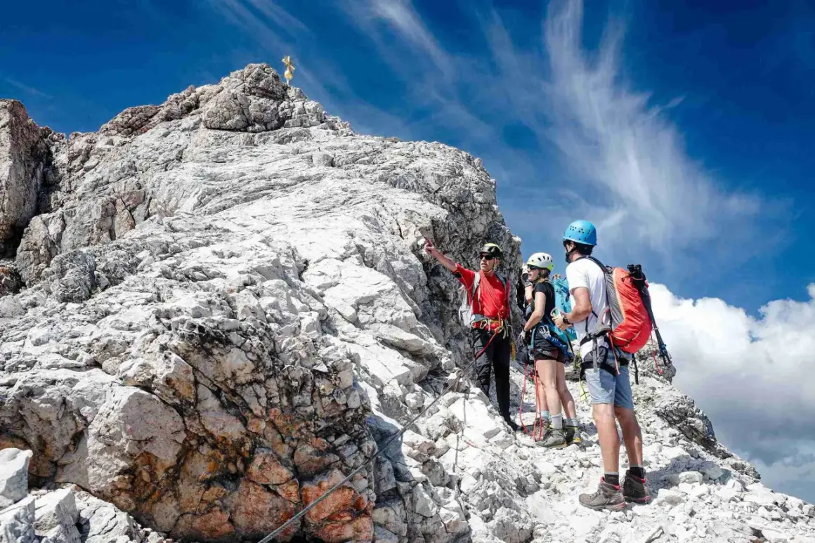 Bergsteiger erklären den Weg zur Zugspitze ohne Klettersteig. Ein Führer zeigt auf den Gipfel.