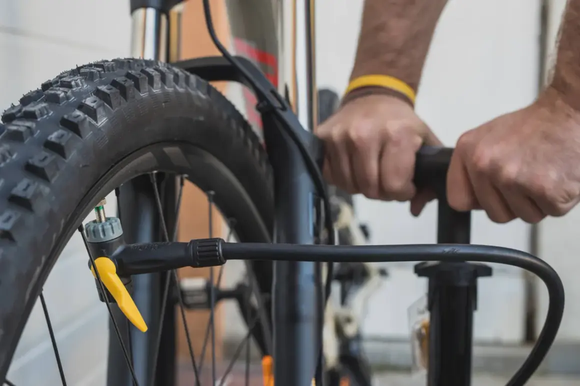 Hände pumpen einen Reifen auf. Der richtige Reifendruck für ein Fahrrad mit 20 Zoll Rädern ist wichtig für die Fahrt.