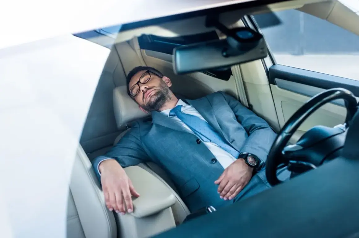 Ein Geschäftsmann im Anzug schläft im Auto. Ob man in Italien im Auto schlafen darf, ist eine andere Frage.