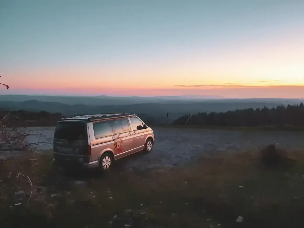 Ein Campervan steht auf einem Hügel bei Sonnenuntergang. Die Frage "was kostet wildcampen" stellt sich hier nicht, denn die Aussicht ist unbezahlbar.