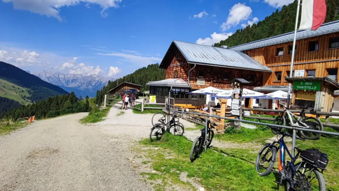 Bergpanorama in den Tuxer Alpen mit Holzhütte, Fahrrädern und E-Bike-Tankstelle.
