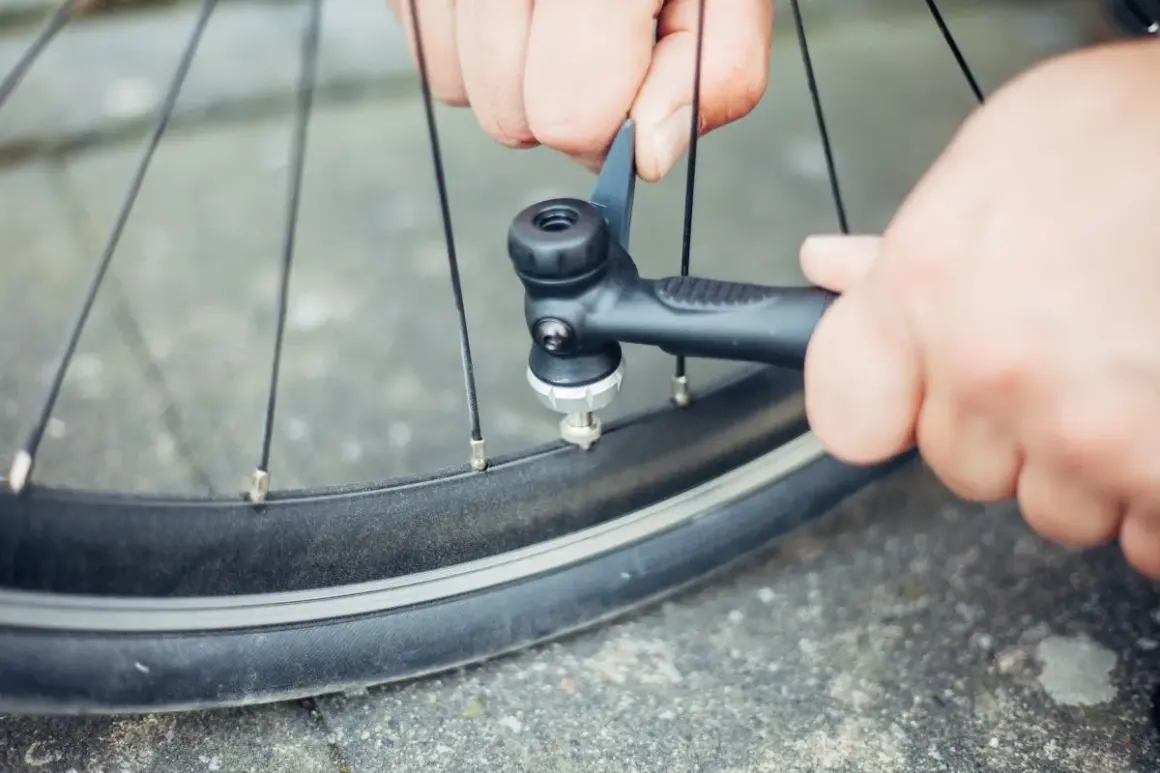 Hände pumpen mit einer kleinen Pumpe ein Fahrrad auf. Ein Reifen wird an einer Tankstelle fahrrad aufpumpen.