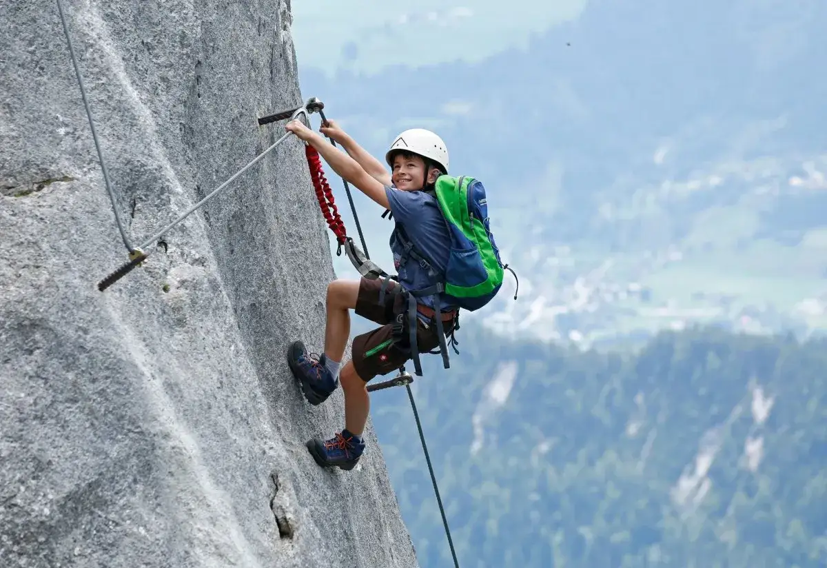 Ein Junge meistert einen Klettersteig, voller Freude und Abenteuerlust. Ein tolles Erlebnis für klettersteig kinder!