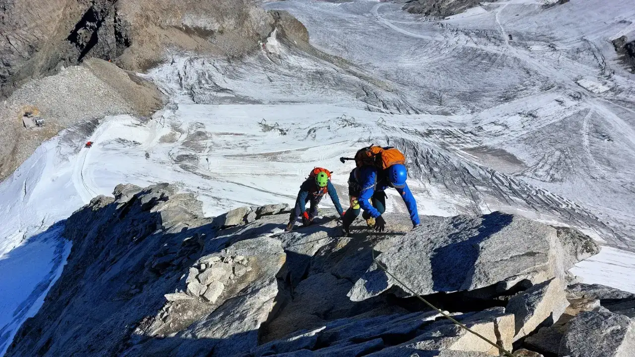 Zwei Bergsteiger klettern &uuml;ber den felsigen Olperer Nordgrat. Im Hintergrund erstreckt sich ein riesiger Gletscher.