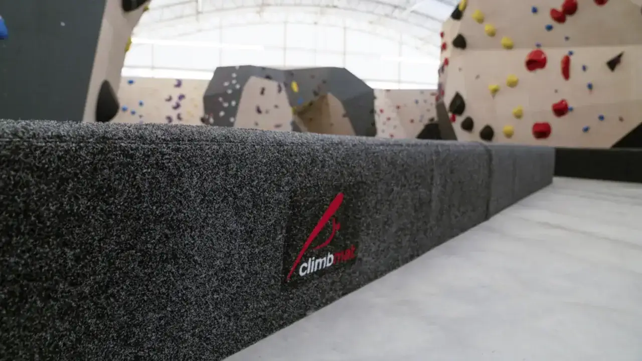 Bouldern: Klettern ohne Seil an niedrigen Wänden mit bunten Griffen. Die dicke Matte schützt vor Stürzen.