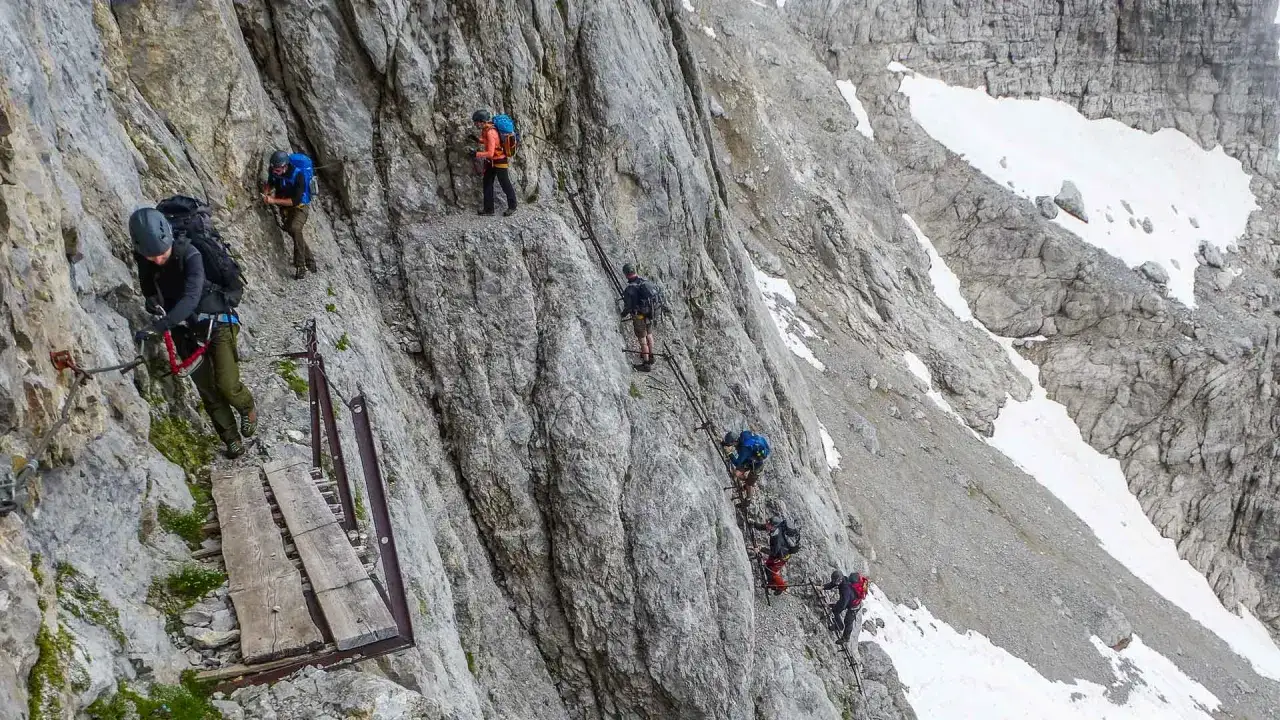 Klettersteig-Begehung in den Brenta Dolomiten. Bergsteiger sichern sich an Stahlseilen auf steilem Fels.