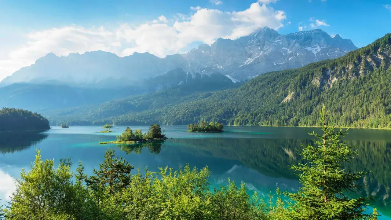 Idyllischer See mit Inseln und bewaldeten H&auml;ngen, im Hintergrund majest&auml;tische Berge. Ein malerischer Anblick in Deutschland.