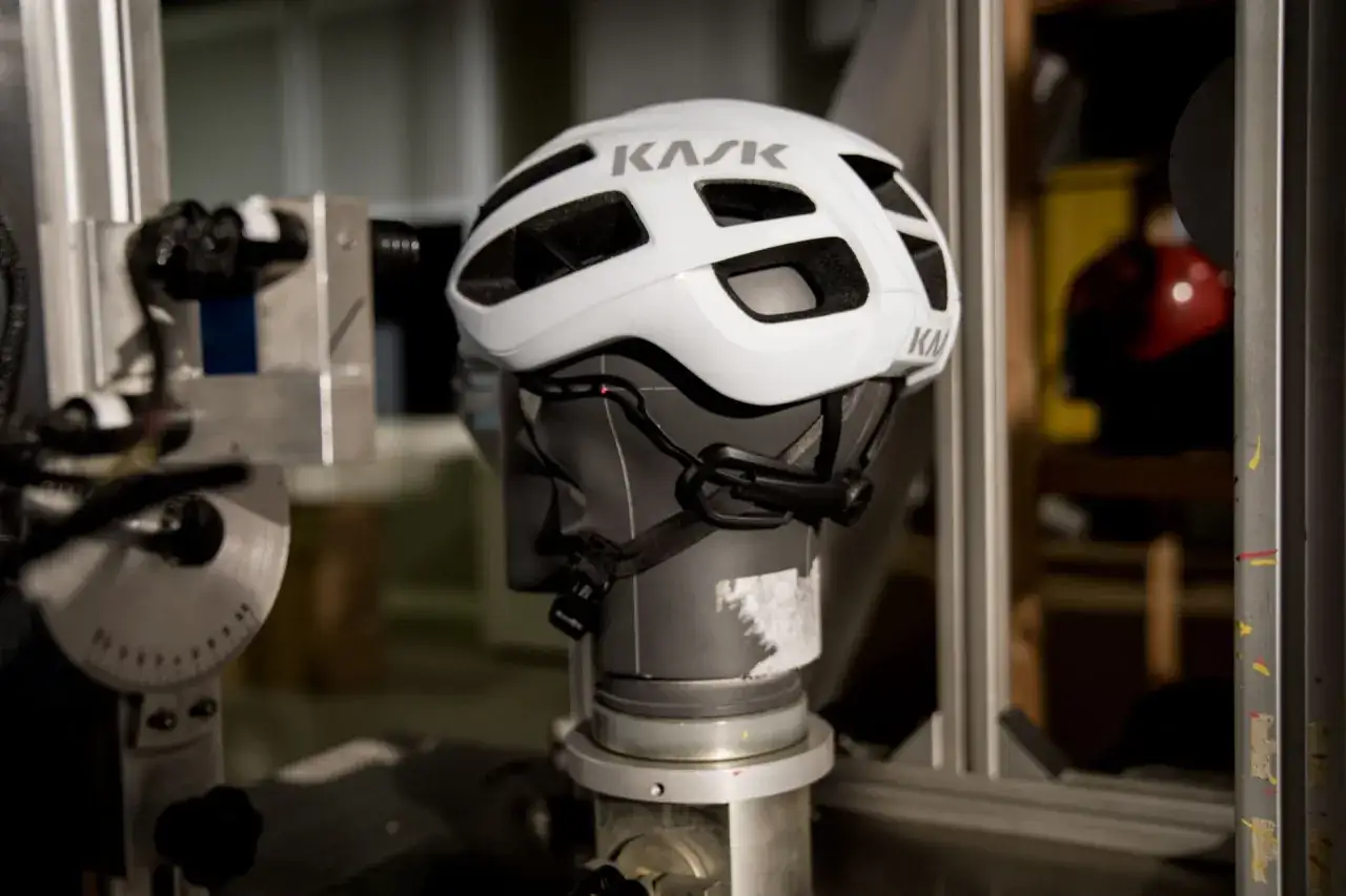 Ein wei&szlig;er Fahrradhelm auf einem Pr&uuml;fstand. Die Technologie, was ist MIPS, sch&uuml;tzt den Kopf bei St&uuml;rzen.