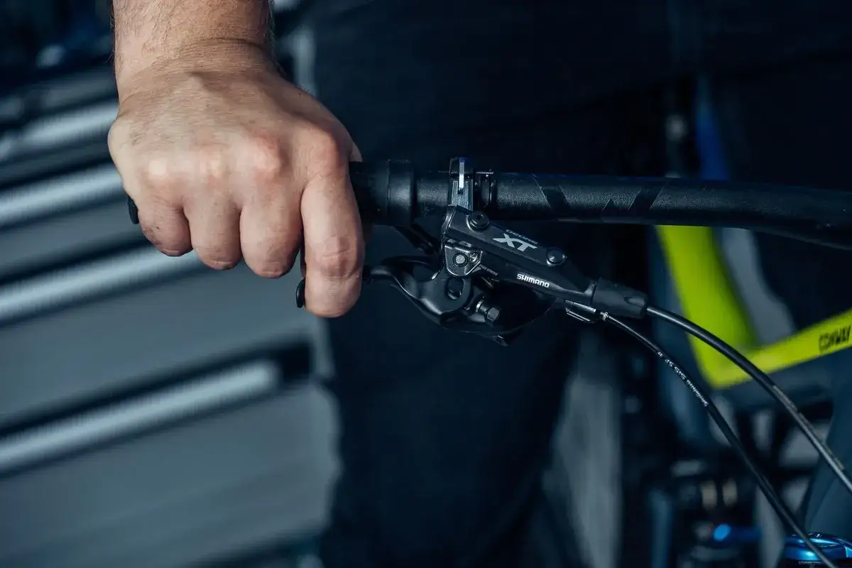 Hand adjusts the bremshebel einstellschraube for optimal braking performance on a mountain bike.