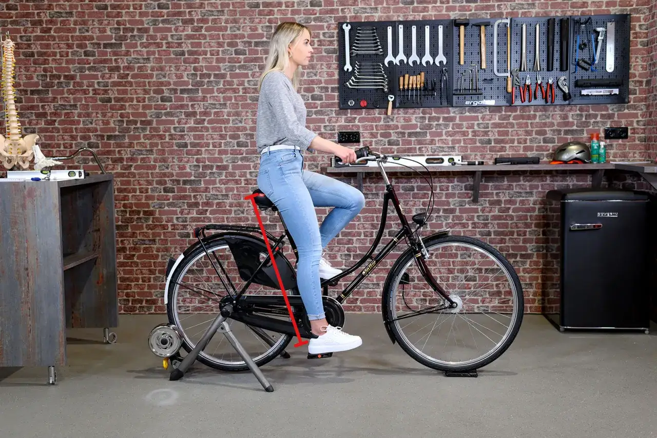 Frau auf Fahrradtrainer, deutliche rote Markierung zeigt, dass der Sattel zu hoch eingestellt ist.