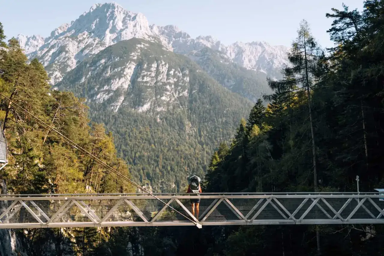 Wanderer auf H&auml;ngebr&uuml;cke mit Blick auf Alpenpanorama bei Mittenwald.