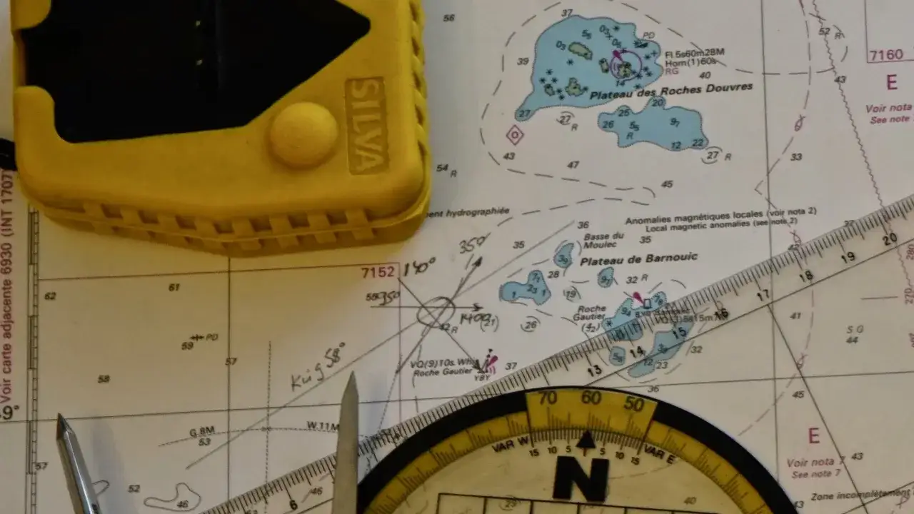 Ein Kompass auf einer Seekarte zeigt, wie man ihn benutzt. Gelbe Navigationshilfen liegen bereit.