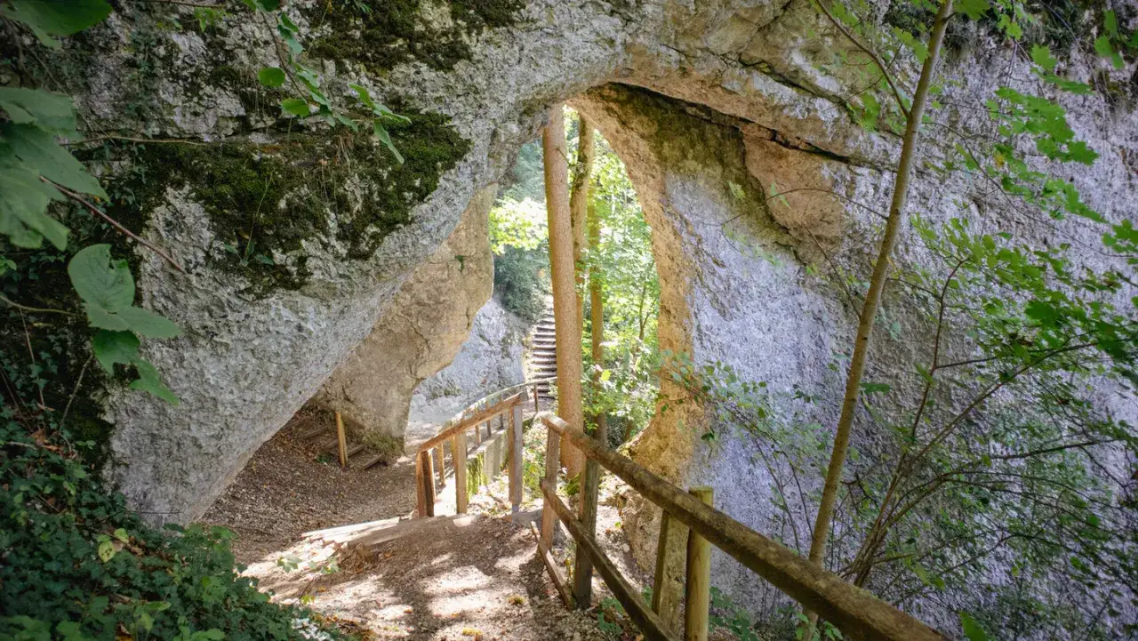 Ein felsiger Durchgang mit Holzgel&auml;nder und Treppen l&auml;dt zum Inzigkofen wandern ein.