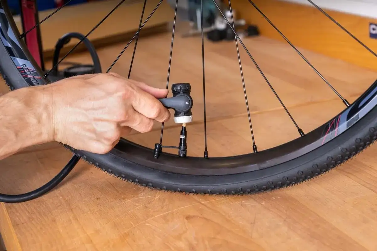 Hand pumpt Fahrradreifen auf. Der Reifen wird mit Luft gef&uuml;llt, um ihn f&uuml;r die Fahrt vorzubereiten.